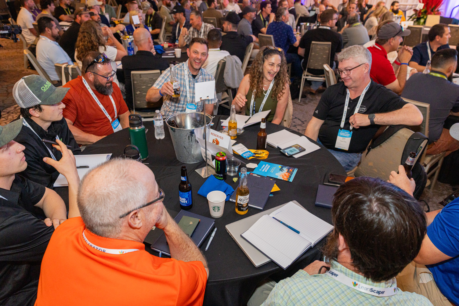 Monique Allen smiling during a leadership mastermind session at LeanScaper Operations Intensive, seated at a roundtable with nine male attendees in Cape Coral, Florida.